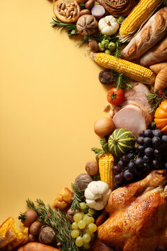 Thanksgiving Still Life with Roasted Turkey, Fresh Bread, Corn and Colorful Autumn Produce on Bright Yellow Background for Seasonal Use