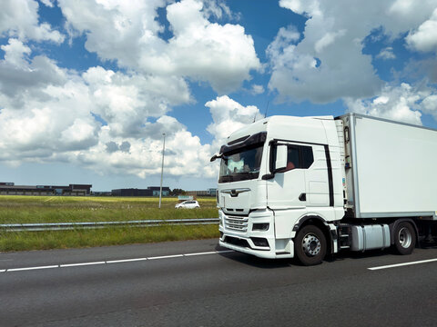 White freight truck on Dutch motorway near Hoofddorp under dramatic clouds, blue sky