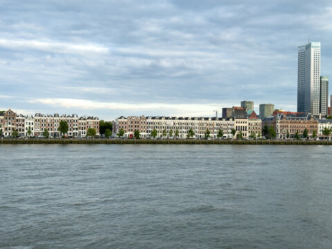 Rotterdam Centrum skyline across river with waterfront homes and modern towers under storm clouds, Netherlands