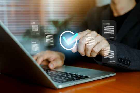 Businessman using a laptop to verify digital documents with a glowing checkmark, representing document approval, data security, workflow automation, and online business management.