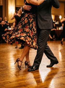 Couple dancing tango on wooden floor at social dance event. Tango dance, ballroom dancing and partner movement. Dance class, performance and cultural tradition. Close view of dancers