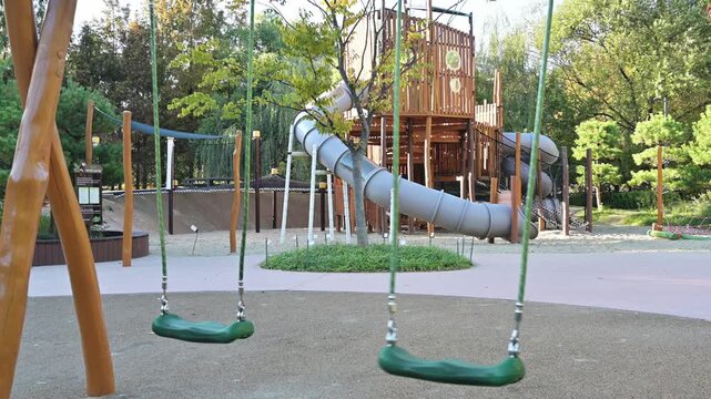 야외 어린이 놀이터에 있는 빈 초록색 그네와 미끄럼틀 놀이기구(Empty green swings and slide play equipment at outdoor children playground in Korea)