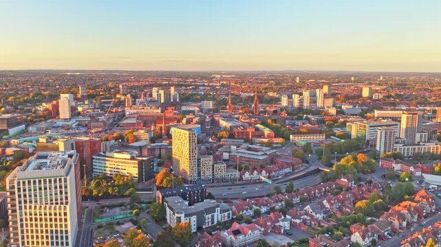 Coventry city centre towers, streets and rooftops in golden hour light in the West Midlands, England, aerial