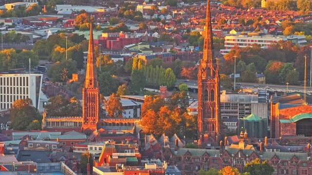 Spires of Coventry Cathedral (ruins of St Michael) and Holy Trinity Church rising above the city centre at golden hour in Coventry, West Midlands, aerial