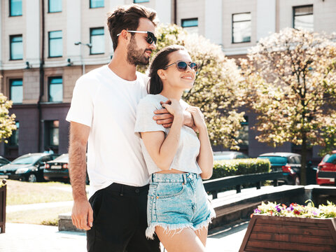 Smiling beautiful woman and her handsome boyfriend. Woman in casual summer clothes. Happy cheerful family. Female having fun. Couple posing on the street background in sunglasses.Hugging each other