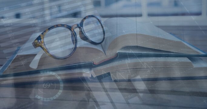 Resting round tortoiseshell eyeglasses on open hardcover book at study desk, with digital charts
