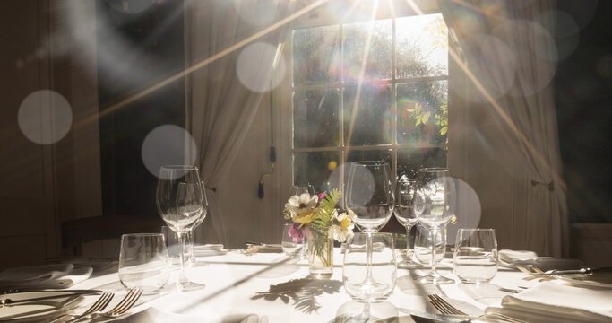 Displaying clear vase holding daisies and wildflowers on dining table near window
