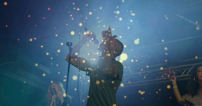 Singing lead singer wearing dark short-sleeve shirt on concert stage with microphones, truss, haze