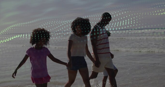 Walking family holding hands at low tide water's edge, wearing purple dress, denim