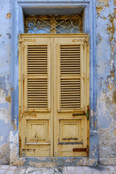 Vintage Yellow Louvered Wooden Front Door Set in Peeling Light Blue Painted Architrave Wall, Malta