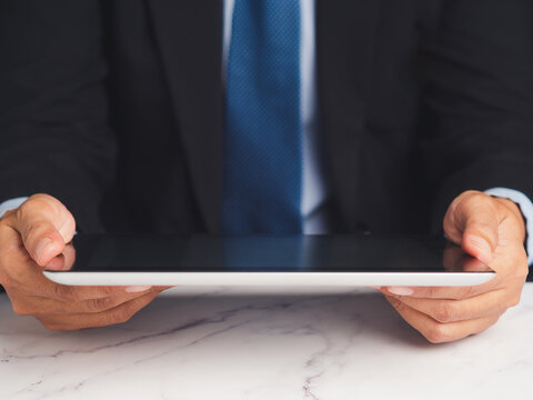 Businessperson in suit holding tablet with both hands  