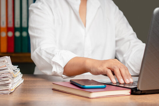 Person typing on laptop at office desk with documents