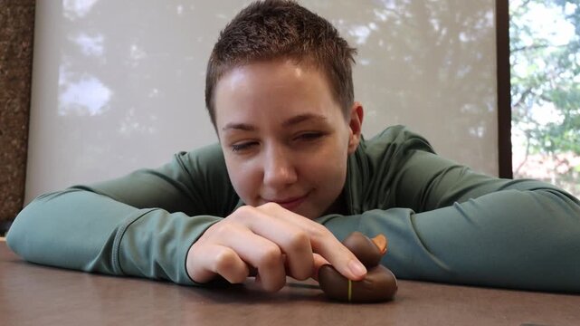 Whimsical football themed rubber duck pushed in slow motion by a young woman across an office table top. Daydreaming about friday night football.