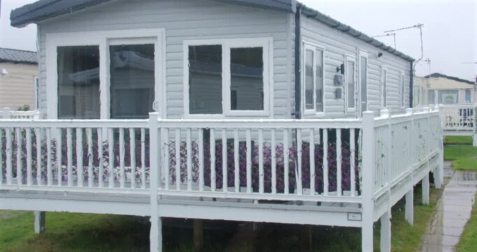 Wide Shot Opening curtain to show rain on a static caravan window with static caravans in background at Fleetwood, blackpool