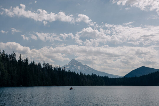 Lone person rows a boat on a lake near a mountain