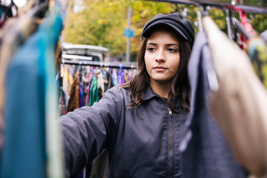 Young woman browses clothes at an outdoor street market
