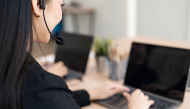 Close Up Side View of Female Call Center Agent Wearing Headset at Office Desk