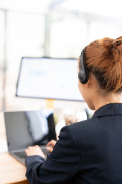 Back View of Female Call Center Agent Wearing Headset and Typing in Vertical Office Setup