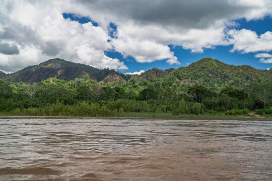 Heavy rain over the Amazon River and forest, with a small boat navigating the water amidst the storm
