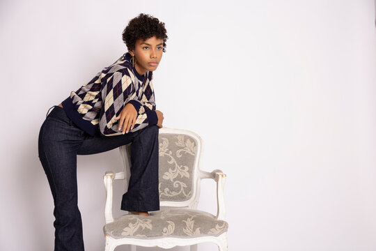Young Hispanic woman posing with armchair in fashion studio
