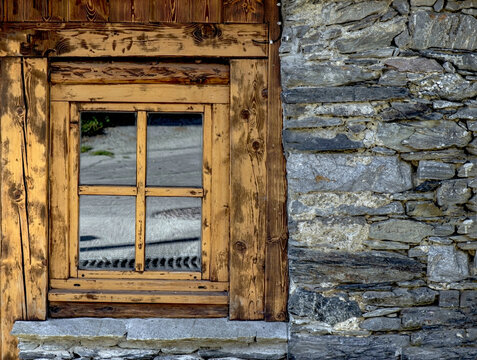 Background stoned wall and wooden window closed from an rustic chalet in Savoie, european Alps