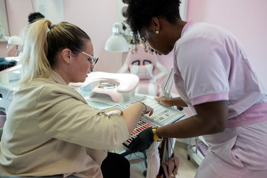 Client choosing nail polish with a salon technician