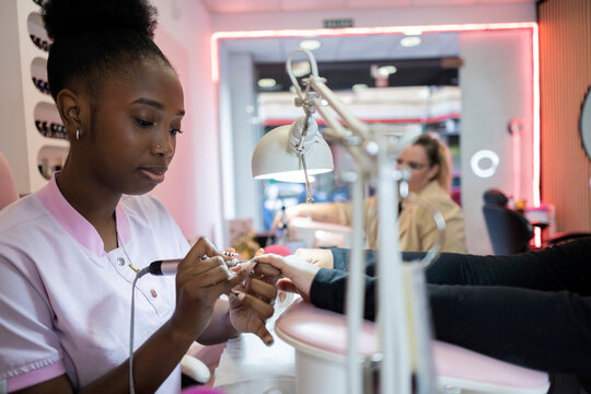 Nail technician performing a manicure with an electric nail drill
