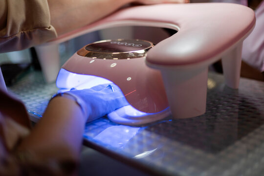 Hand curing gel nails under a uv manicure lamp