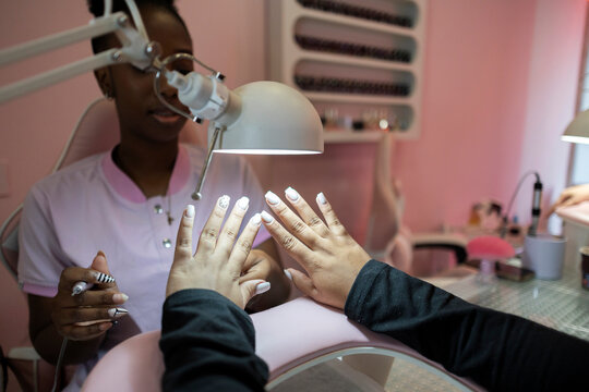 Nail technician filing decorated nails during a salon manicure