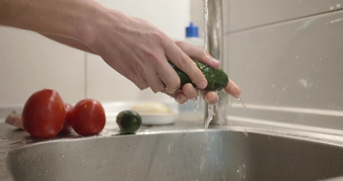 Close-up male hand wash rinse cucumber under tap water in sink. 4K 10-bit