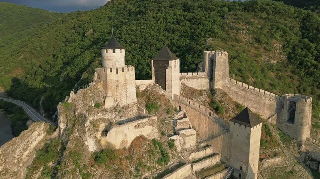 Aerial view of Golubac medieval fortress on cliff above Danube river at sunset, historic landmark in Serbia, 4k