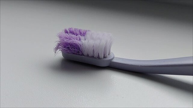 Extreme close up of old worn out toothbrush head with bent purple and white bristles, dental hygiene mistake and timely toothbrush replacement concept stock asset.