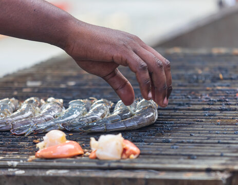 A man is cooking shrimp on a grill