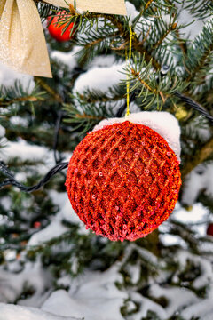 A Christmas and New Year tree is decorated with bright ornaments and covered in snow. The scene shows winter elements and holiday decorations
