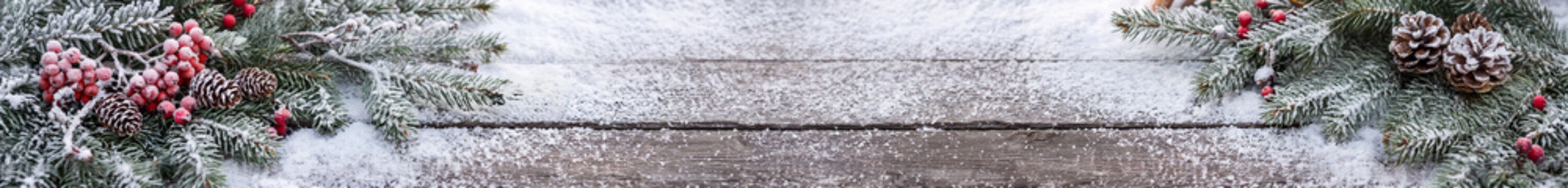 Christmas Banner of Snowy Fir Branches Cones and Red Berries on Wood with copy space