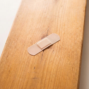 Bandage on cracked wood concept for quick temporary fix home repair humor and caring for damaged household surfaces