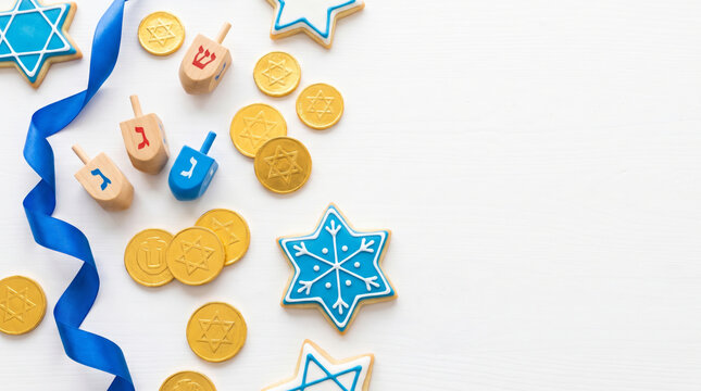 Blue ribbon, dreidel, gelt and Hanukkah table setting with star cookies. Community friend generation gathering together faith invitation