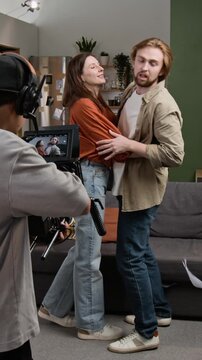 Vertical video of young adult Caucasian actors finishing scene and celebrating with film crew giving high fives on set. Clip fits media production campaigns