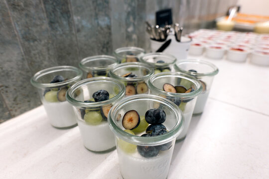 Panna cotta or yogurt desserts with fresh berries and grapes in glass jars on a catering table