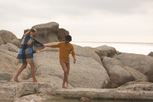 Caucasian couple walking on rock near beach