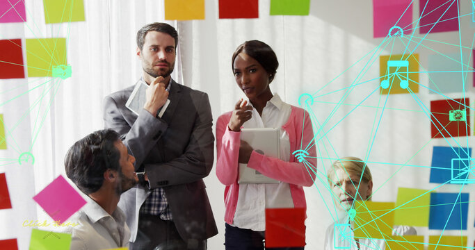 Image of globe of digital icons over diverse businesspeople discussing over memo notes at office