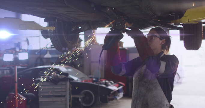 Image of light over caucasian female mechanic fixing car