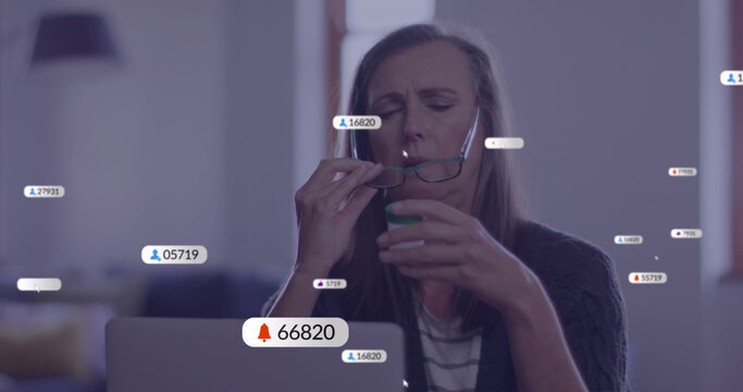 Image of social media icons with numbers over senior caucasian woman using laptop