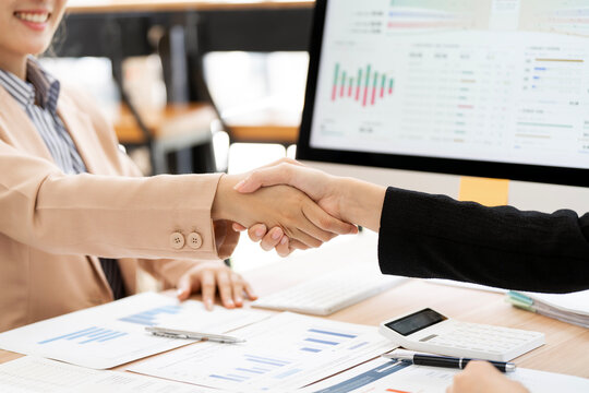 Close Up of Businesswomen Handshake over Financial Report Documents at Desk