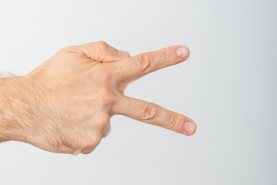 Caucasian male hand representing a scissors gesture from the game rock paper scissors, expressing competition, selection, or an option against a clean backdrop
