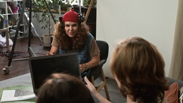 Young adult Caucasian director discussing script with colleagues over shoulder during creative studio meeting. Footage suits marketing campaigns on video production