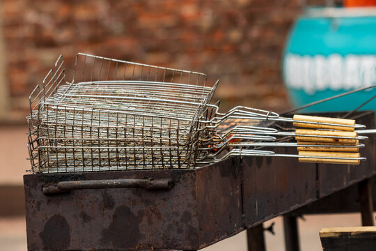 Metal grill basket rests on rustic barbecue