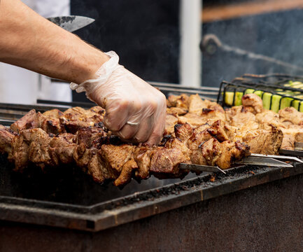 Hand flips sizzling meat on grill with tongs