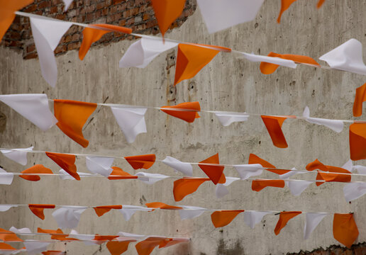 Orange and white paper flags hang against a weathered wall