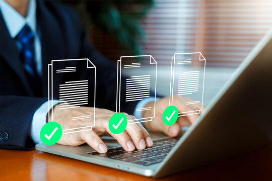 Business person using a laptop with glowing digital document icons and green checkmark approval symbols. Concept of compliance, document verification, quality control, and successful workflow.